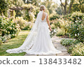 A bride walks through a rose garden in a white train dress. 138433482
