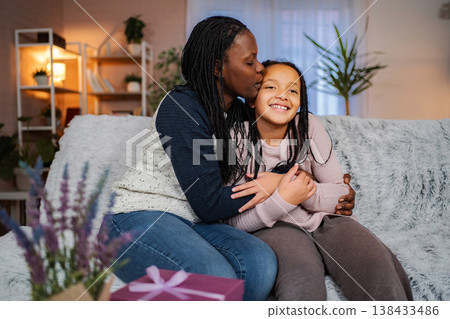 Mother kissing daughter's forehead showing love and togetherness 138433486