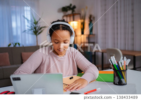 Young girl learning drawing online with wireless headphones Young girl learning drawing online with wireless headphones 138433489