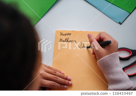 Young girl writing Happy Mothers Day card for mom Young girl writing Happy Mothers Day card for mom 138433497