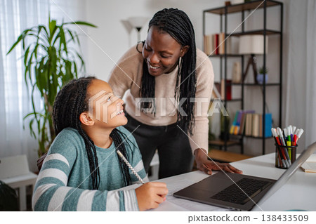 Mother helping daughter with homework using laptop at home Mother helping daughter with homework using laptop at home 138433509