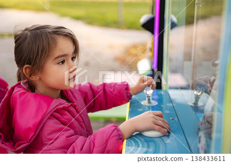 Little girl concentrating playing crane claw game 138433611