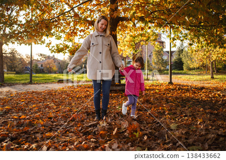 Mother and daughter enjoying walk in autumn park Mother and daughter enjoying walk in autumn park 138433662