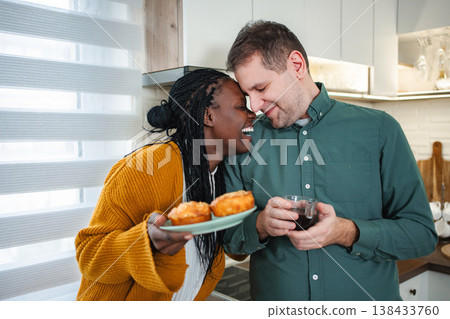 Interracial couple sharing happy morning with muffins and coffee Interracial couple sharing happy morning with muffins and coffee 138433760