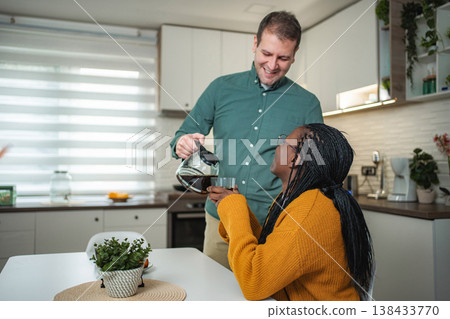 Happy couple enjoying morning coffee together in kitchen 138433770