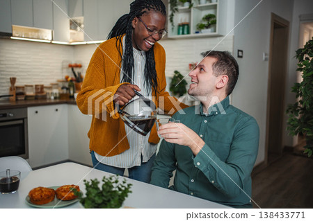 Happy interracial couple enjoying breakfast together in kitchen Happy interracial couple enjoying breakfast together in kitchen 138433771