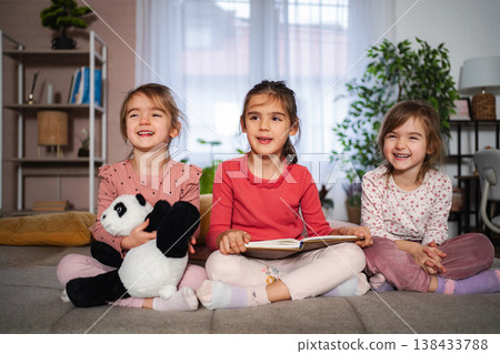 Three happy young sisters enjoying story time at home Three happy young sisters enjoying story time at home 138433788