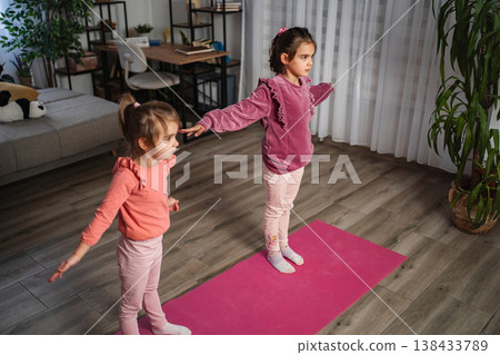 Little sisters practicing yoga stretching exercises on floor at home Little sisters practicing yoga stretching exercises on floor at home 138433789