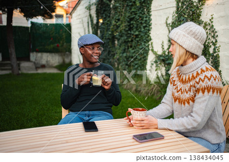 Two women friends having tea and coffee in backyard Two women friends having tea and coffee in backyard 138434045