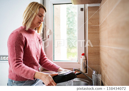 Woman washing pan in kitchen sink at home 138434072