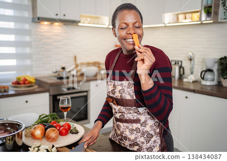 Happy woman smelling fresh carrot cooking healthy food 138434087