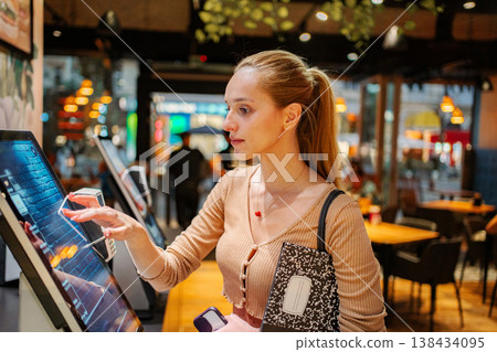 Young woman using self-service kiosk at restaurant in Vienna 138434095