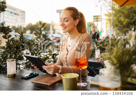 Woman enjoying Aperol Spritz and using tablet in Vienna Woman enjoying Aperol Spritz and using tablet in Vienna 138434108