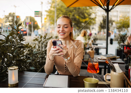 Smiling woman using smartphone at outdoor cafe in Vienna Smiling woman using smartphone at outdoor cafe in Vienna 138434110