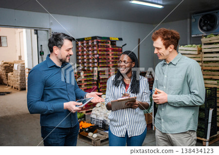 Produce team discussing logistics in cold storage warehouse Produce team discussing logistics in cold storage warehouse 138434123