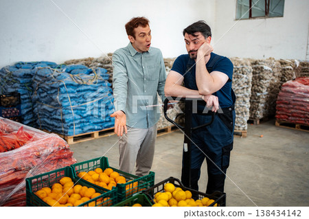 Manager discussing with worker in fruit and vegetable warehouse 138434142