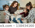 Woman and children petting a small dog at home 138434160