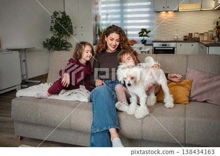 Mother and children bonding with dog on sofa at home Mother and children bonding with dog on sofa at home 138434163
