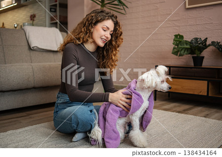 Woman drying white dog with purple towel after bath Woman drying white dog with purple towel after bath 138434164