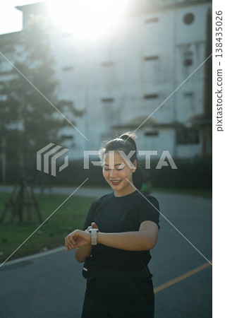 Women pausing during run, checking fitness progress with smartwatch tracking Women pausing during run, checking fitness progress with smartwatch tracking 138435026