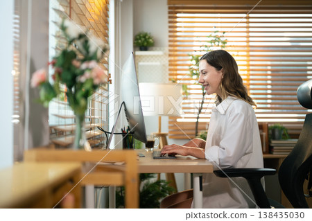 Smiling remote worker with computer at desk in bright home workspace 138435030