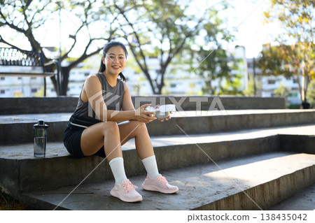Portrait woman resting and listening to music during outdoor workout break in park Portrait woman resting and listening to music during outdoor workout break in park 138435042