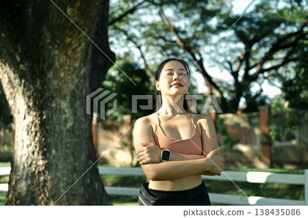 Relaxed woman breathing deeply with eyes closed in green park during workout break, mindfulness and healthy lifestyle concept 138435086