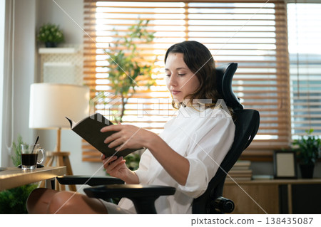 Focused woman studying with coffee at modern workspace indoors. 138435087