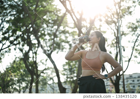 Fit female athlete with a water bottle and taking a break after exercise 138435120