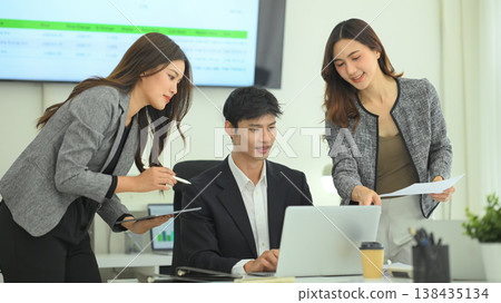 Team discussing strategy around laptop in office Team discussing strategy around laptop in office 138435134