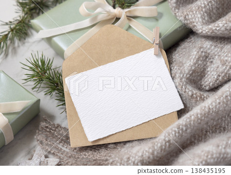 Christmas card mockup on wrapped sage green gift box with fir branches and knitted blanket Christmas card mockup on wrapped sage green gift box with fir branches and knitted blanket 138435195