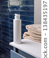 White flip top cosmetic bottle near beige bath towel in blue bathroom, cosmetic mockup 138435197