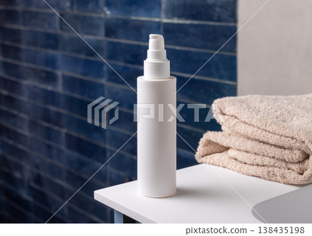 White pump cosmetic bottle near beige bath towel in dark blue bathroom, cosmetic mockup White pump cosmetic bottle near beige bath towel in dark blue bathroom, cosmetic mockup 138435198