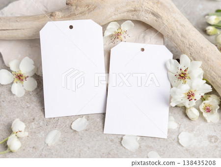 Blank vertical gift tags mockup with white spring flowers and driftwood on light stone, label design Blank vertical gift tags mockup with white spring flowers and driftwood on light stone, label design 138435208