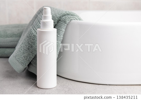 White pump cosmetic bottle mockup near sage green bath towel in bathroom. Unbranded packaging White pump cosmetic bottle mockup near sage green bath towel in bathroom. Unbranded packaging 138435211