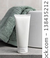 White blank cream tube near sage green towel in bathroom close up, unbranded cosmetic mockup 138435212