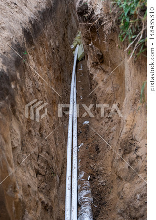 Insulated water pipe in earth trench, underground installing, utility line, site groundwork, plumbing protection, channel excavation, dirt covering, repair. Insulated water pipe in earth trench, underground installing, utility line, site groundwork, plumbing protection, channel excavation, dirt covering, repair. 138435310