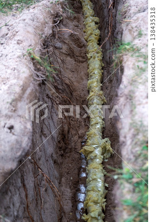 Insulated water pipeline in ground, plumbing protection, trenchwork installation, covered utility tube, groundwork, residential, repair, site, channel excavation. Insulated water pipeline in ground, plumbing protection, trenchwork installation, covered utility tube, groundwork, residential, repair, site, channel excavation. 138435318