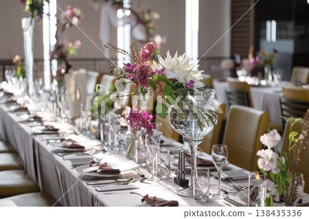 自然光線充足的婚禮宴會場地，鮮花佈置和餐桌擺設。 138435336