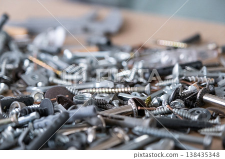 Pile of metal fasteners: bolts, nuts, screws, washers and nails, essential for repair, assembly, construction, and production works in workshops. Pile of metal fasteners: bolts, nuts, screws, washers and nails, essential for repair, assembly, construction, and production works in workshops. 138435348