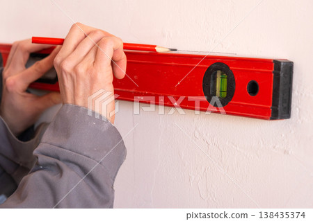 Accurate wall marking with level and pencil, construction layout solution, renovation start, interior alignment, setup for mounting or repair. Accurate wall marking with level and pencil, construction layout solution, renovation start, interior alignment, setup for mounting or repair. 138435374