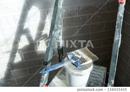 Wall finish upgrade in process, painting supplies and tools, stepladder workspace, home improvement project, interior decor, room repair works. 138435435