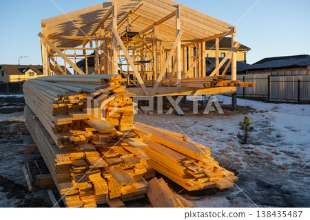 Timber beams delivery for house frame, material stacked on construction site, foundation prep, wood support elements, carpentry supply, project organization. 138435487
