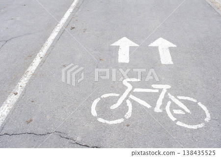 Bicycle path sign and arrows painted on city road, safe route for cyclists, urban road marking, following traffic rules. Bicycle path sign and arrows painted on city road, safe route for cyclists, urban road marking, following traffic rules. 138435525