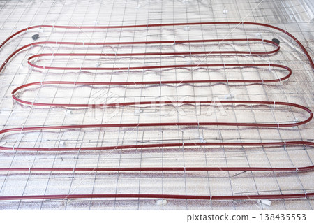Installing underfloor heating system, laying heating pipes on insulation, floor heating installation, construction and renovation work, energy efficiency. 138435553