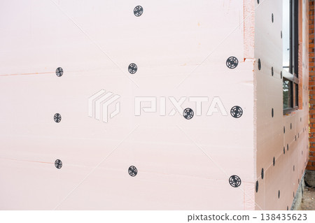 Insulation panel closeup, facade thermal board installation, foam on external wall, energy-saving mount, waterproofed house renovation, modern construction. Insulation panel closeup, facade thermal board installation, foam on external wall, energy-saving mount, waterproofed house renovation, modern construction. 138435623
