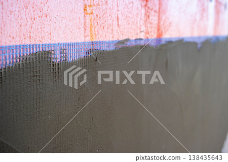 Application of exterior plaster over reinforcement mesh on house wall, facade finishing, wall strengthening, insulation protection, stucco construction. Application of exterior plaster over reinforcement mesh on house wall, facade finishing, wall strengthening, insulation protection, stucco construction. 138435643