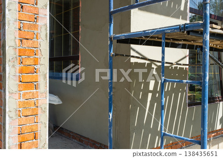 Facade finishing, plasterwork on mesh, scaffolding for wall coating, leveling and insulation, surface protection in construction renovation process. Facade finishing, plasterwork on mesh, scaffolding for wall coating, leveling and insulation, surface protection in construction renovation process. 138435651