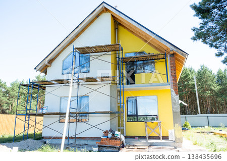 House exterior painted over plaster, scaffolding remains, finish render, detail timber boards for half-timbered facade, renovation and construction complete. House exterior painted over plaster, scaffolding remains, finish render, detail timber boards for half-timbered facade, renovation and construction complete. 138435696