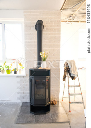 Installed wood stove fireplace in new home during construction stage, mounted on special hearth base, house heating installation and preparation. 138435698